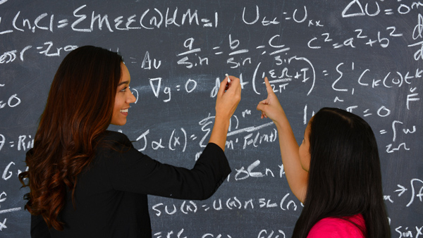 elearning provider in UK and Worldwide expert teacher helping young girl with formulas and mathematics on classroom chalk board